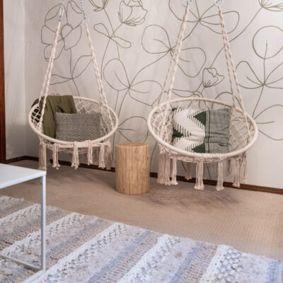 hanging chairs in front of a green floral line art mural