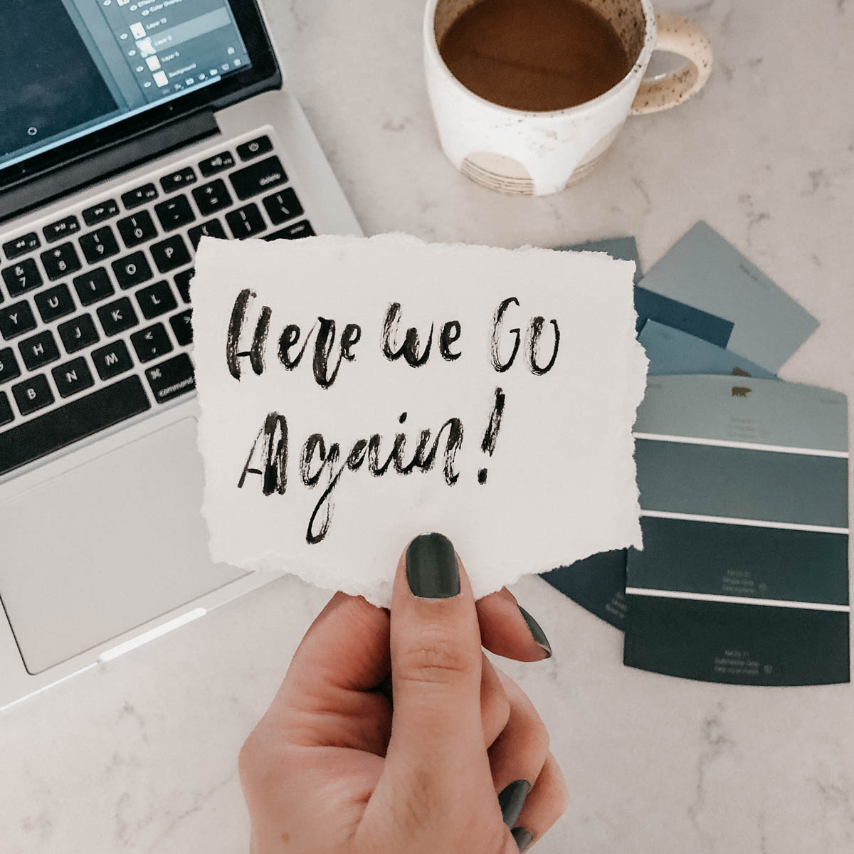 Here we go again! hand lettered on paper, held above paint chips, coffee and computer