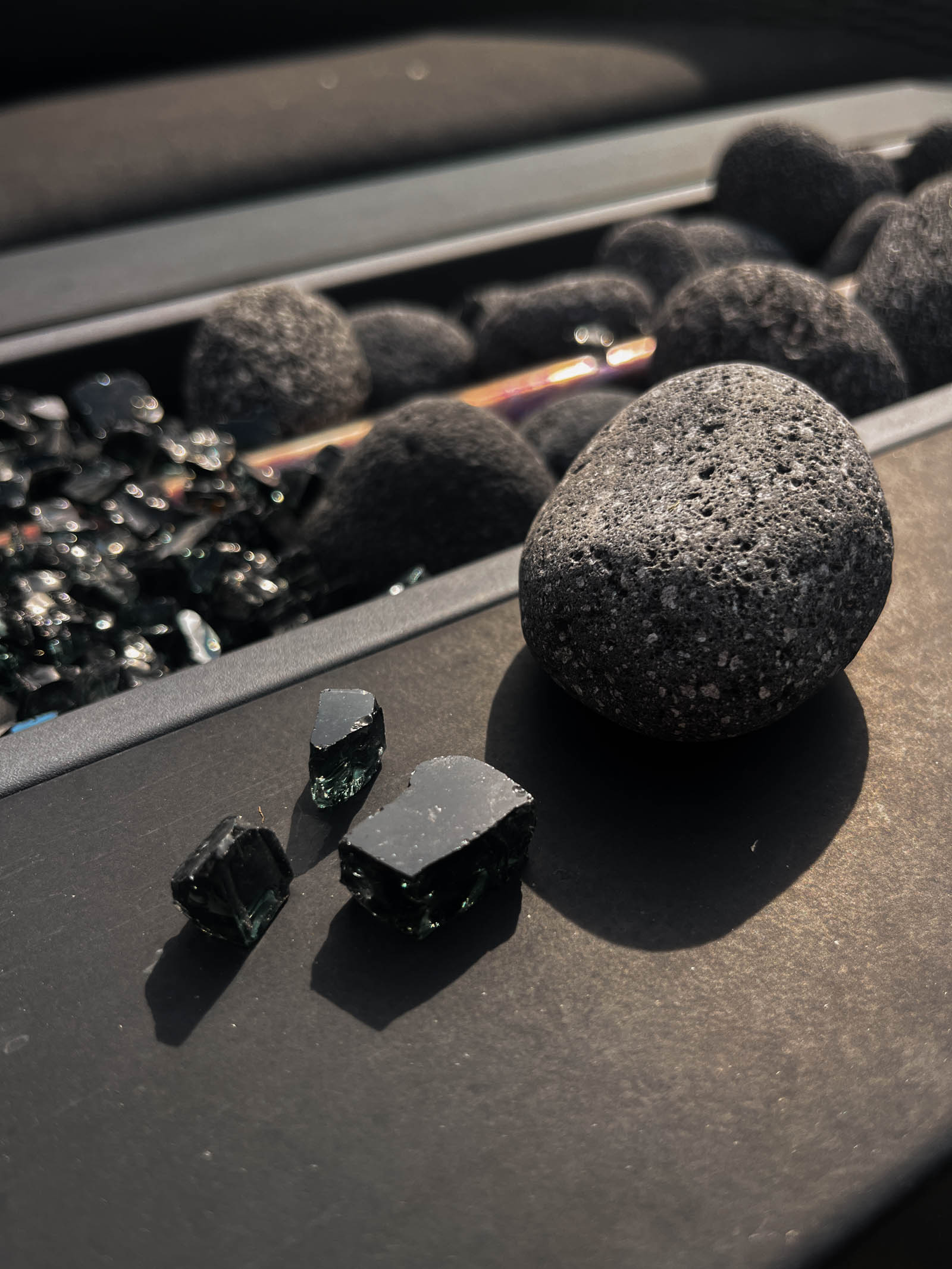Fire glass or fire rocks? Comparing reflective fire glass in black and grey lava pebbles for a modern looking fire table.
