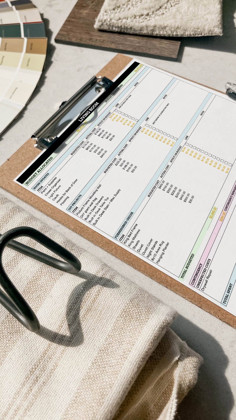 Free room makeover budgeting spreadsheet on clipboard surrounded by design samples