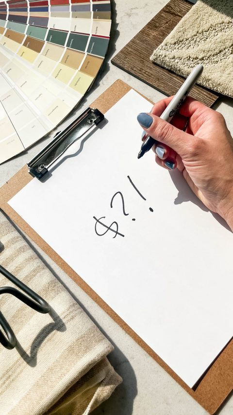 clipboard with dollar signs in sharpie, surrounded by room makeover supplies and samples