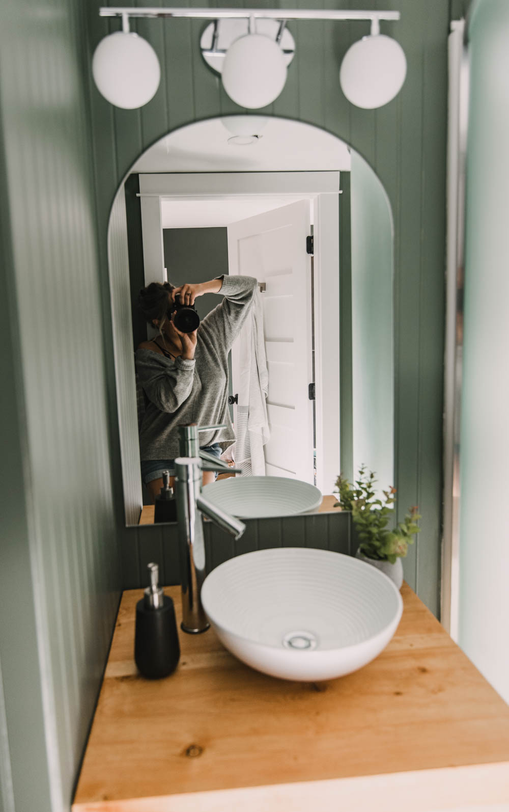 image of dark green bathroom with wood vanity, vessel sink and black and white flooring