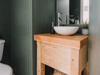 Basement Bathroom remodel - image of finished space with dark green beadboard, wooden vanity and chrome fixtures