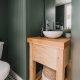 Basement Bathroom remodel - image of finished space with dark green beadboard, wooden vanity and chrome fixtures