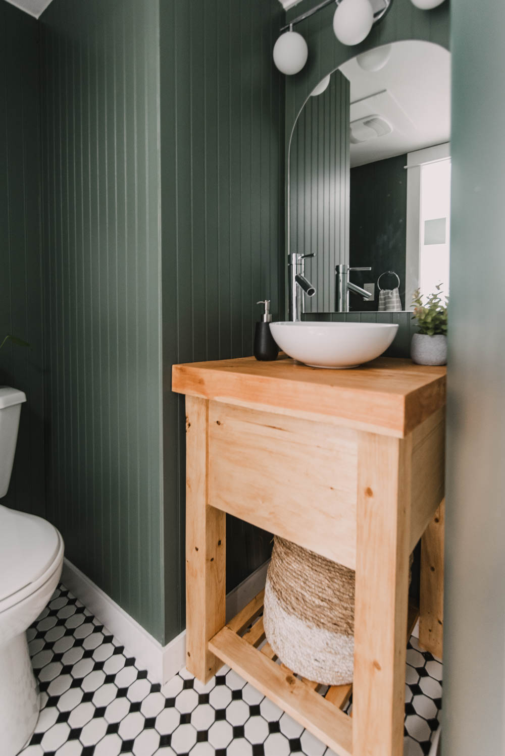 Basement Bathroom remodel - image of finished space with dark green beadboard, wooden vanity and chrome fixtures