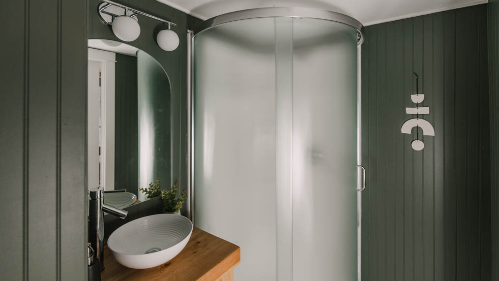 dark green beadboard, wooden vanity and chrome fixtures, small corner shower