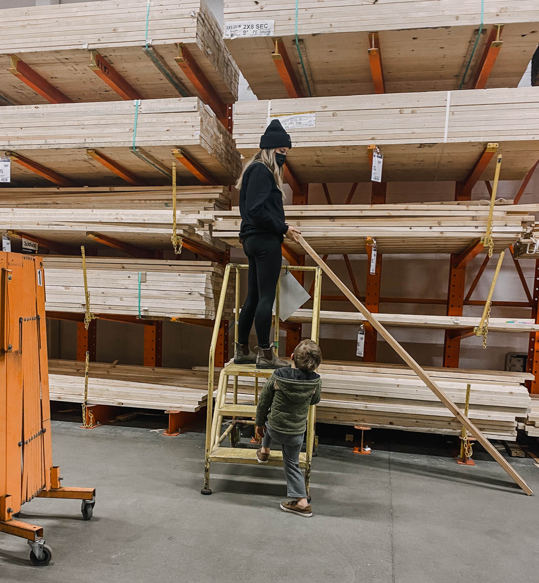 image of woman choosing wood in a hardware store lumber section by looking down the length of a board for warping image from blog post thats a introduction to the types of wood available for DIY projects