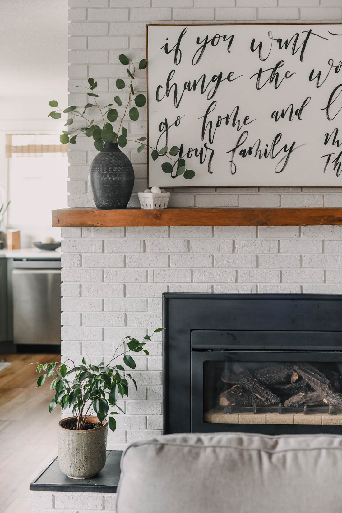 a small weeping fig on the hearth of a white brick fireplace