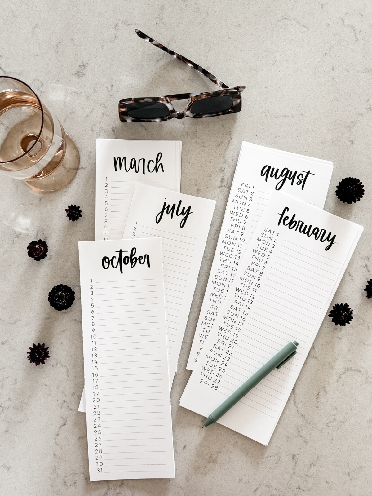 simple hand lettered list calendars free printable for 2025 both dated and perpetual, shown printed off on a marble countertop